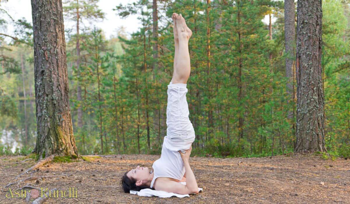 photo of woman doing shoulder stand yoga pose in forest