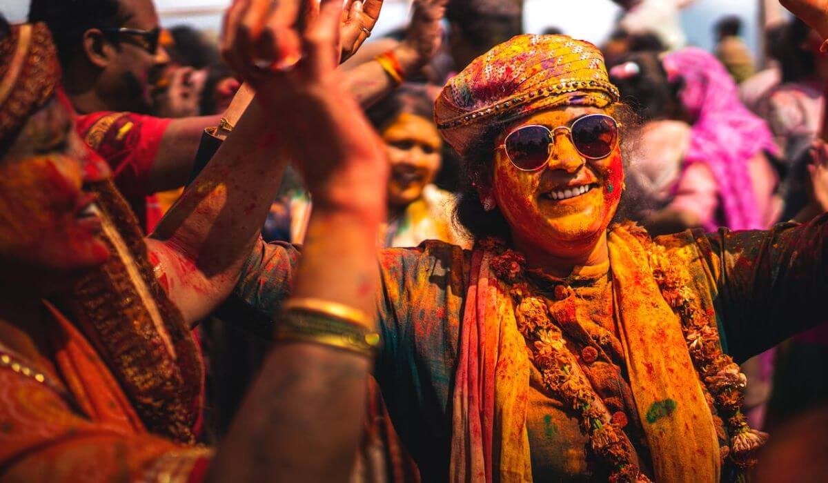 people with colored powder applied on them celebrating holi